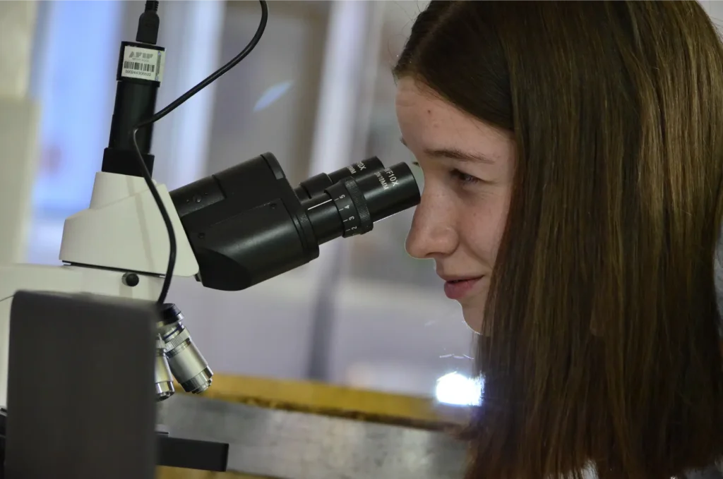 Estudiante mirando por microscopio